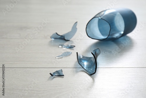 Broken blue glass vase on wooden floor, closeup photo