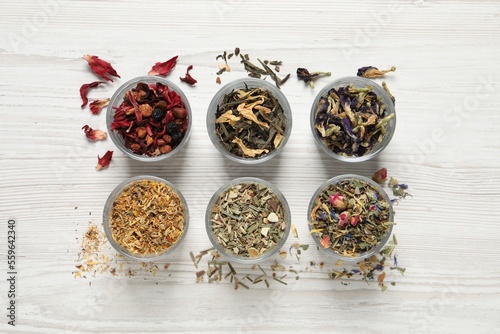 Flat lay composition with different dry teas on white wooden table