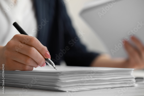 Slika na platnu Woman signing documents at white wooden table in office, closeup