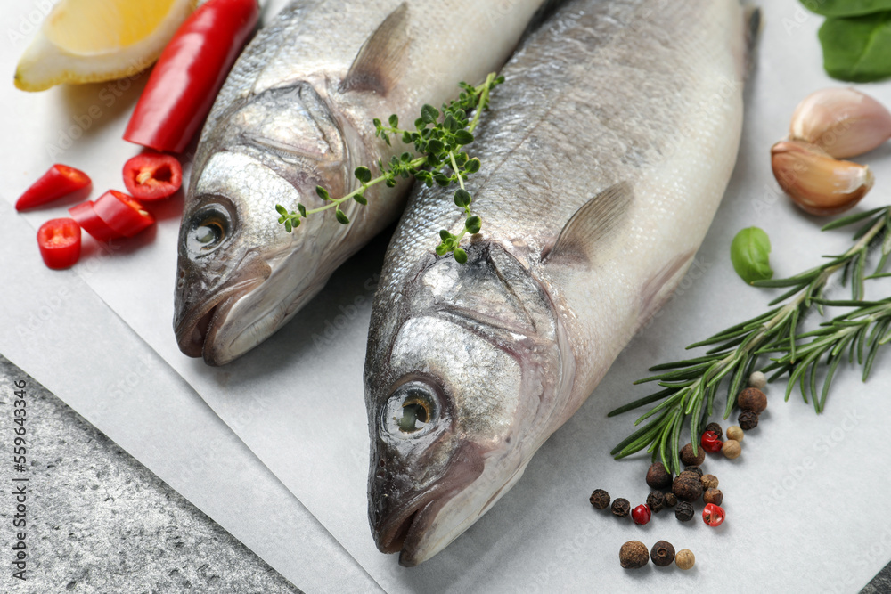 Sea bass fish and ingredients on grey table, closeup Sea bass fish and ingredients on grey table, closeup