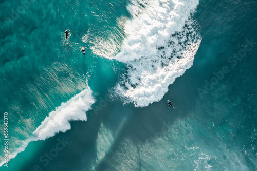 Surfers are seen from above in blue pristine ocean water © FRPhotos