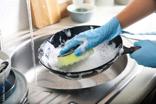 Obraz na plátně Woman washing dirty frying pan in sink indoors, closeup