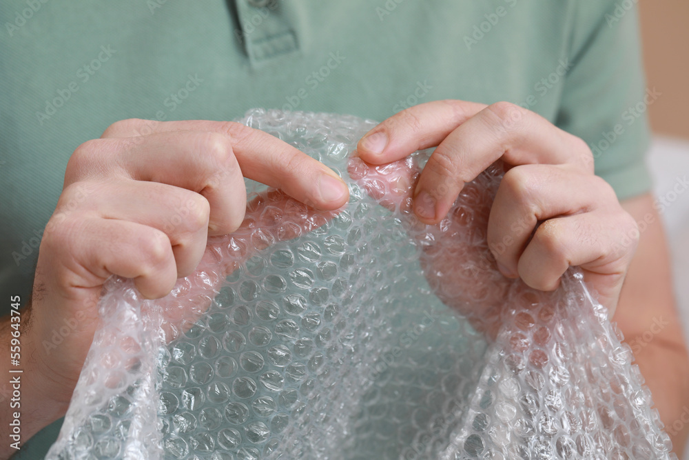 Man popping bubble wrap, closeup view. Stress relief Man popping bubble wrap, closeup view. Stress relief