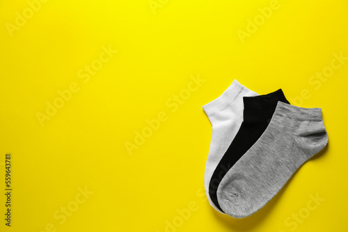 Different socks on yellow background, flat lay. Space for text