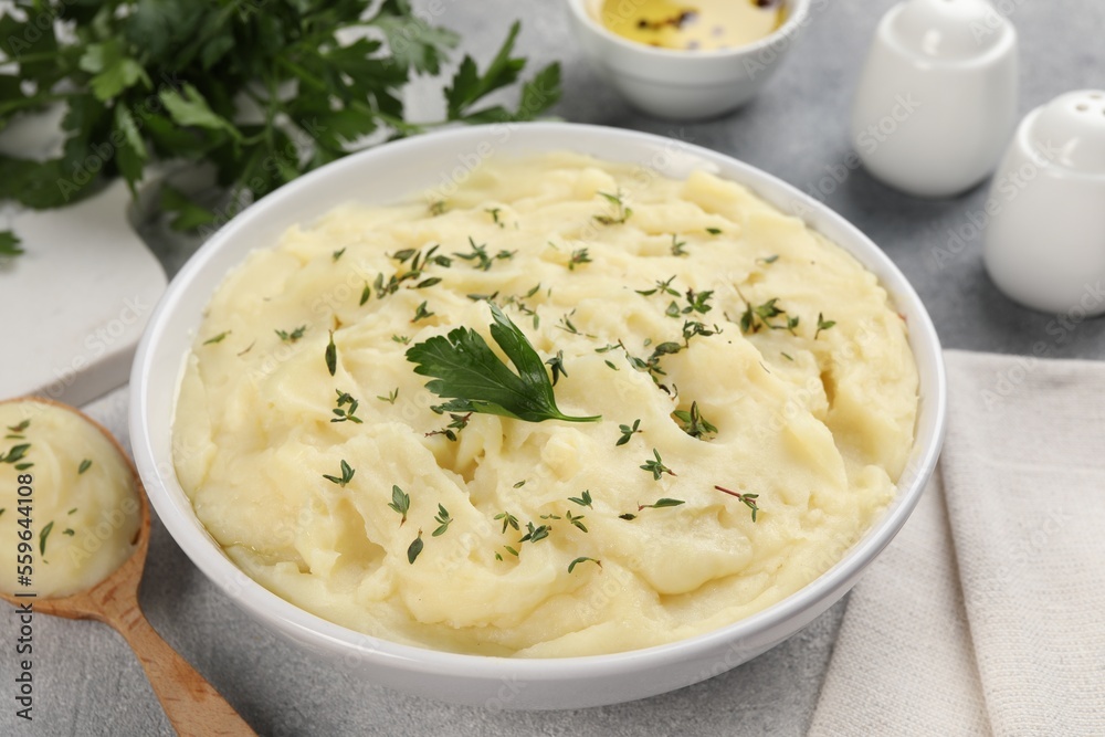 Bowl of tasty mashed potato, parsley, olive oil and pepper on grey marble table, closeup Bowl of tasty mashed potato, parsley, olive oil and pepper on grey marble table, closeup