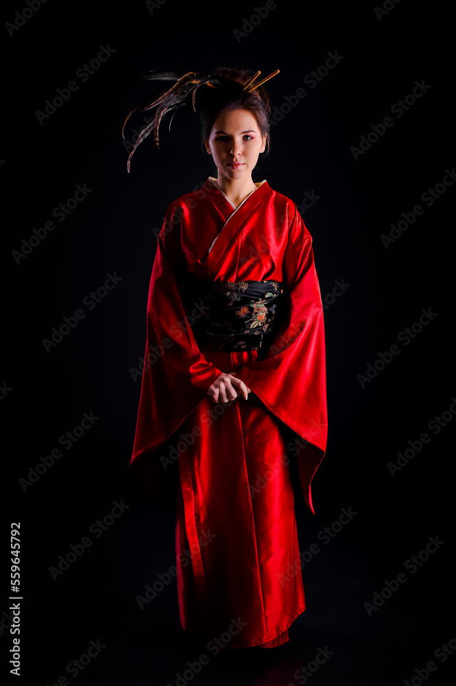 The girl in native costume of japanese geisha, against the black background