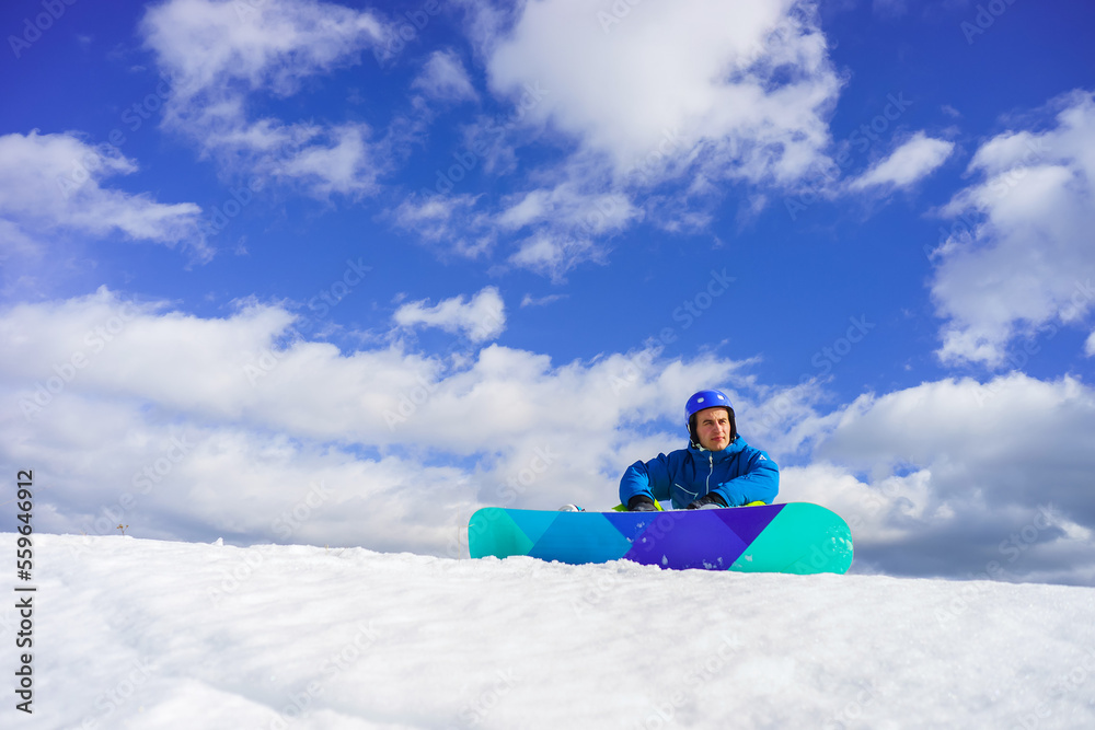 young man with snowboard sit on the snow