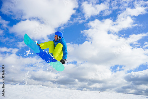 young man on the snowboard jumping over the slope in winter