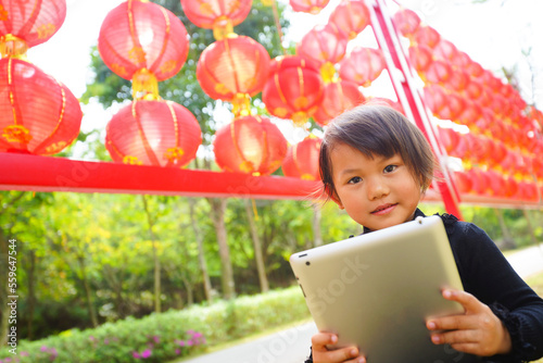 Canvas Print Outdoor portrait of cute small asian girl with tablet