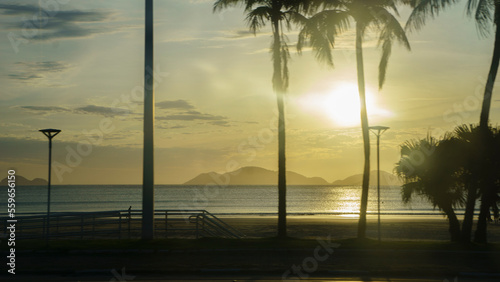 sunset on beach boardwalk with coconut trees and mountain in summer