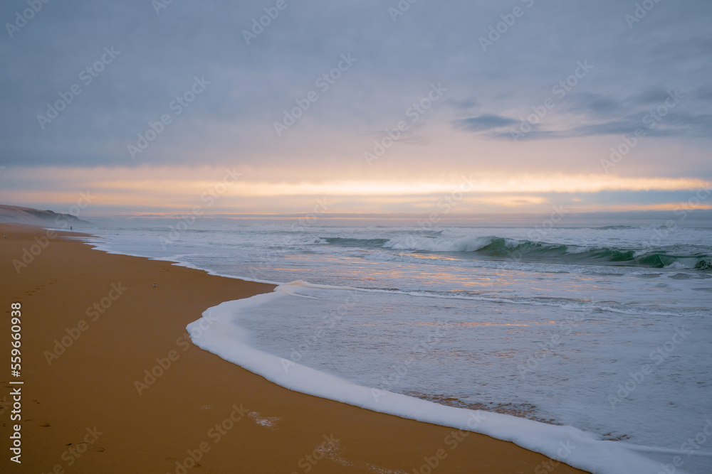Wide sandy beach, stormy sea, and beautiful cloudy sky. Sunset over the sea, copy space for the text