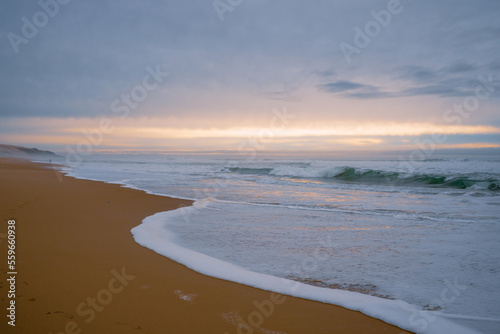 Wide sandy beach  stormy sea  and beautiful cloudy sky. Sunset over the sea  copy space for the text