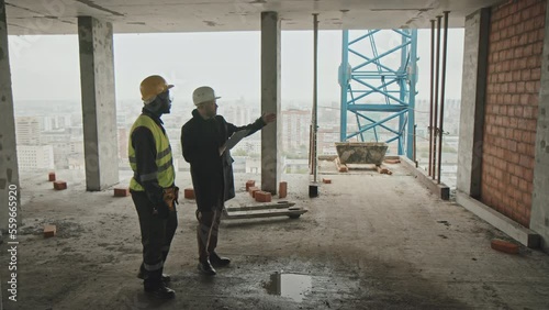Wallpaper Mural Mature Caucasian foreman and young adult Black builder walking along construction site discussing work plan Torontodigital.ca