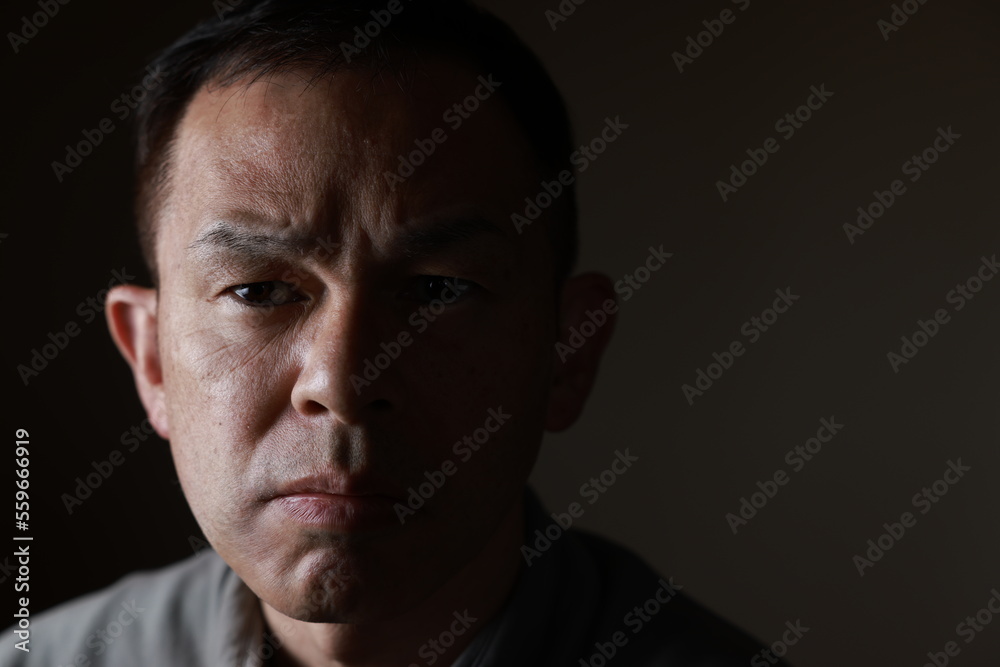 Middle-aged Japanese man in gray casual shirt on gray background. Conceptual image of world peace, stability in daily life, and sustainable living.