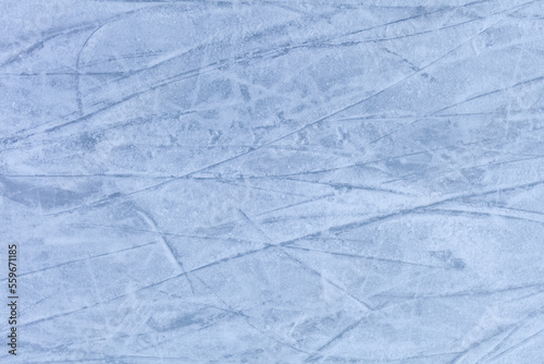 Empty ice rink with skate marks after the session outdoor. skating ice rink texture covered with snow in daylight. Close up of blue ice rink floor  copy space