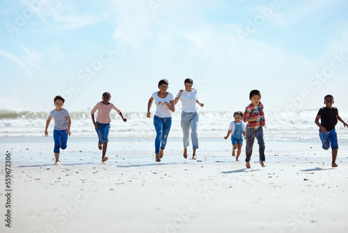 Summer, beach and a group of children running on sand, friendship and fun on ocean holiday. Friends, kids and energy in youth, happy boys and girls on vacation in playful race together at the sea.