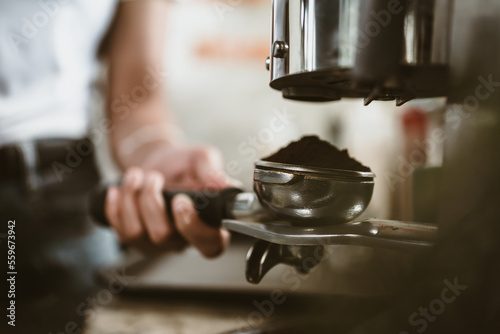 barista use bottomless filter with grinder machine at coffee shop. coffee maker concept.