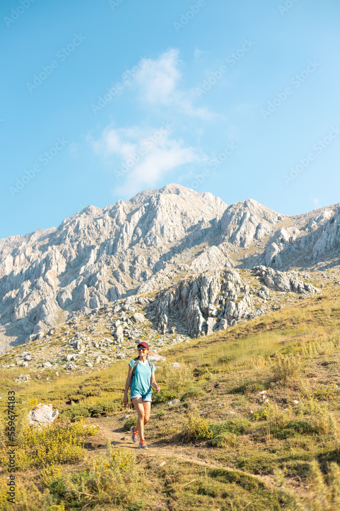 a traveler with a backpack walks along a mountain path. a girl walks in the mountains.