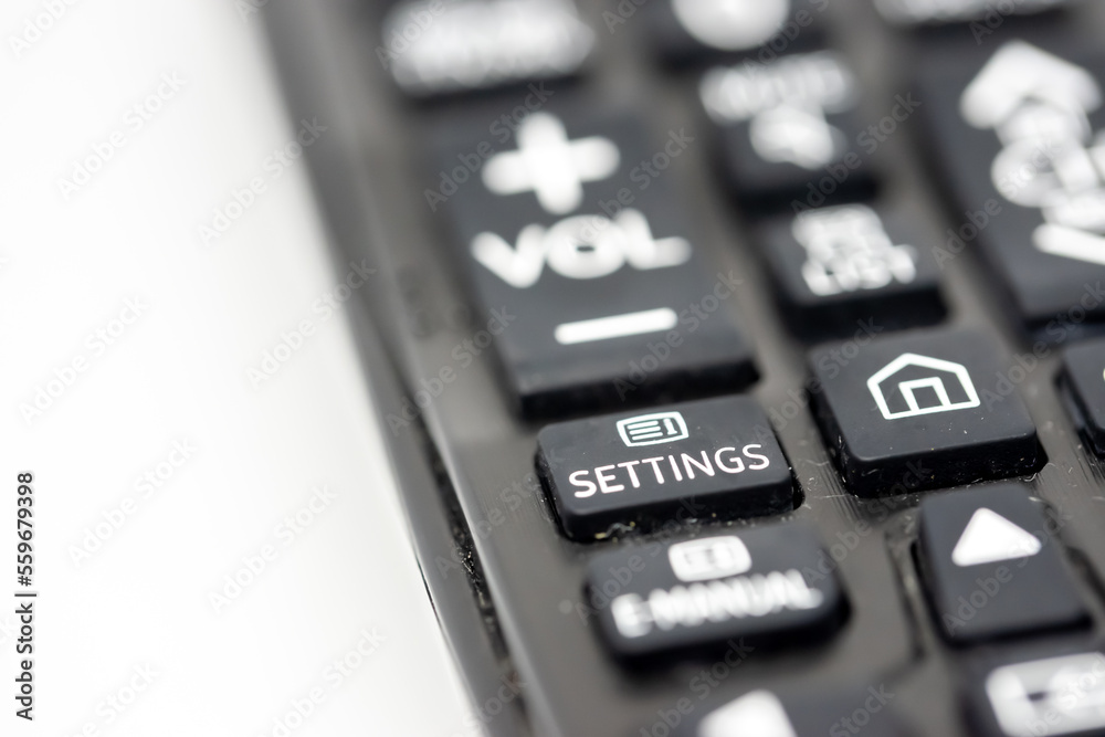 Close-up of a TV remote control with focus on the settings button Close-up of a TV remote control with focus on the settings button
