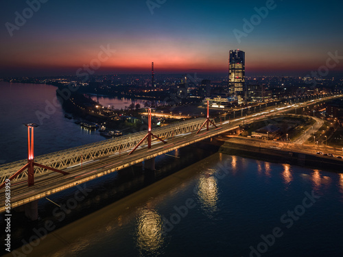 Budapest, Hungary - Aerial view of Rakoczi bridge above River Danube with traffic lights and Budapest's new skyscraper building (MOL Campus) at background at sunset. Blue and red sky at dusk