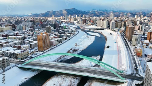 winter aerial view of Sapporo, Hokkaido, northern Japan, flying above frozen river in downtown Sapporo