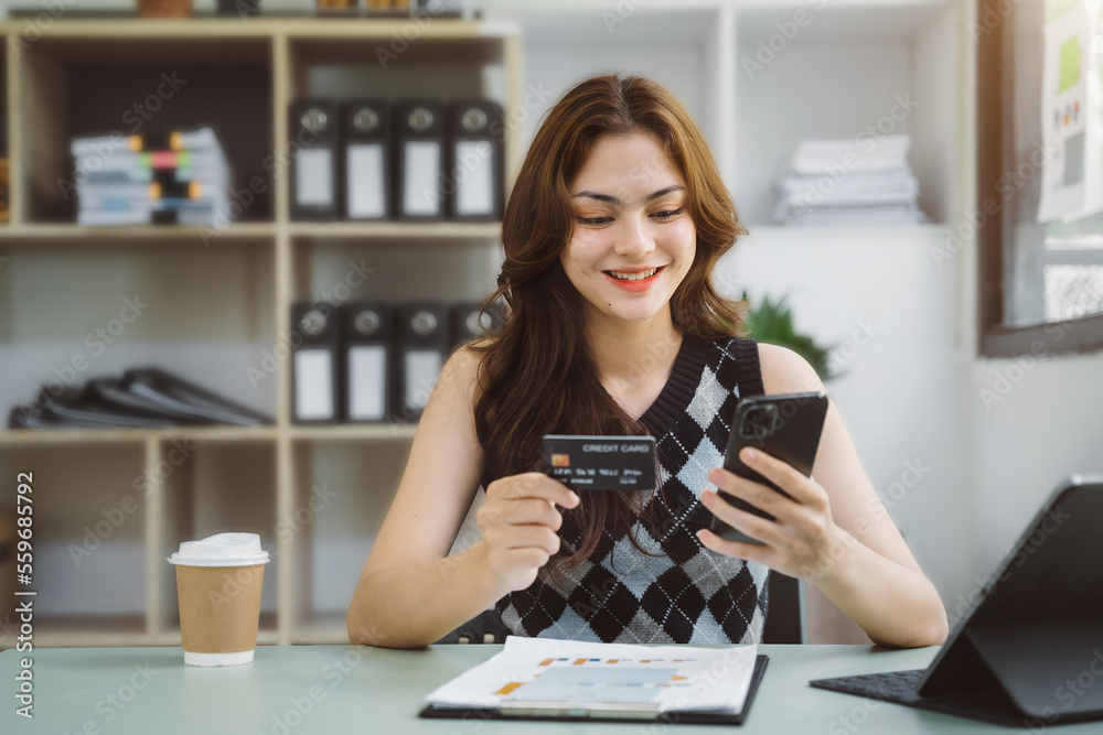 Female asian use credit cards to conduct financial transactions through phones, tablet at home office. Female asian use credit cards to conduct financial transactions through phones, tablet at home office.