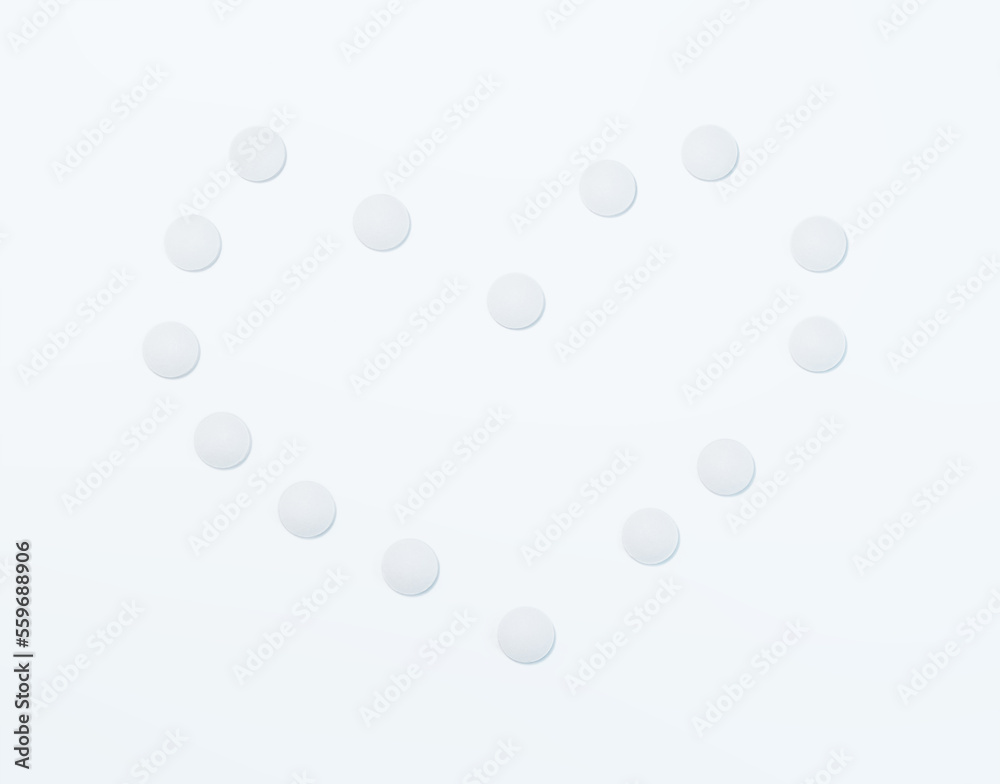 White pills displayed in the shape of a heart on white background