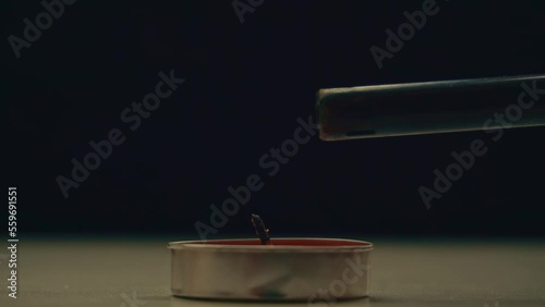 Lighting a candle standing on a table, on a black background. Selective soft selective focus. Scented candle for incense