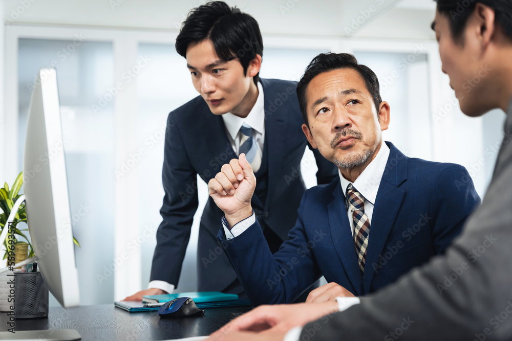 パソコン画面を見ながら会議するビジネスマンのグループ
