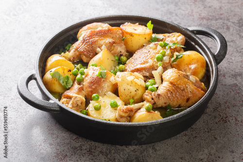 Chicken pieces with potato wedges and roasted in a lemon garlic white wine sauce close-up in a frying pan on the table. Horizontal