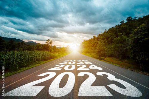 New year 2023 or straight forward concept. Text year 2023, 2024, 2025 written on the road in the middle of asphalt road with at sunset. Concept of planning, goal, challenge, new year resolution.