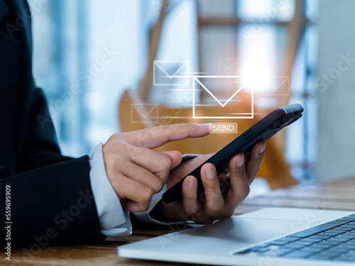 Sending Email and business marketing concepts. Fast moving of digital letters icon appearing while business person using, mobile smart phone and laptop computer at workplace, send message. photo