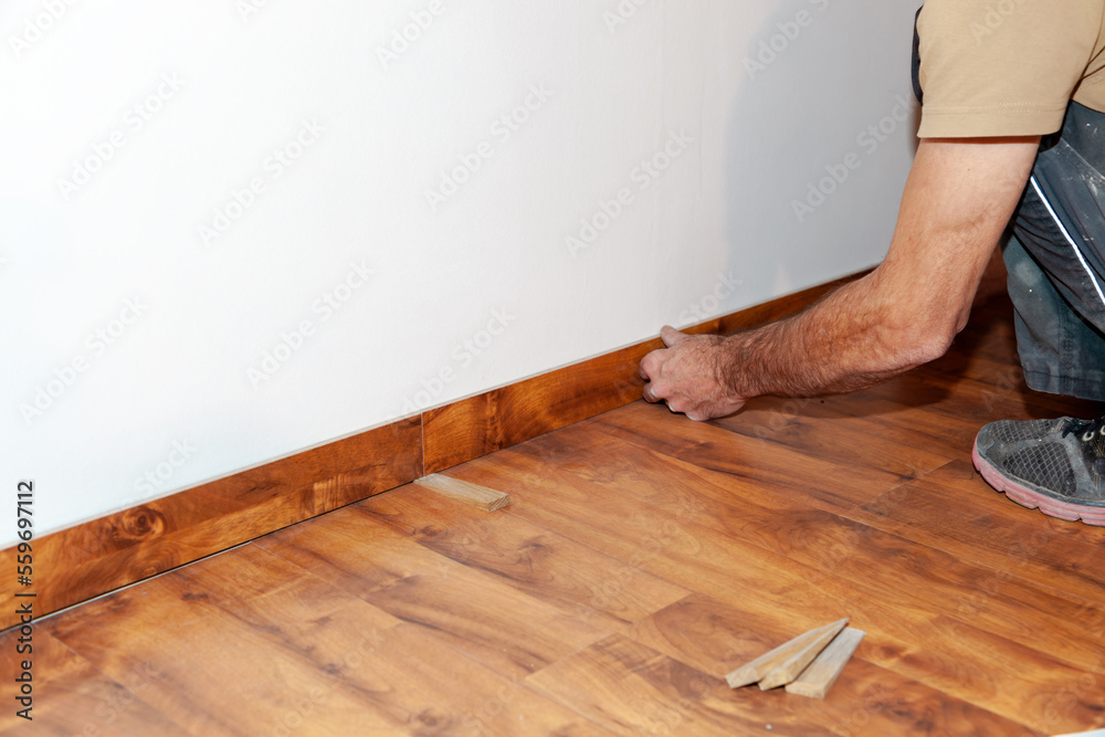 Worker, Carpenter installing laminate flooring. Installing molding trim Vinyl Plank Flooring. Worker, Carpenter installing laminate flooring. Installing molding trim Vinyl Plank Flooring.