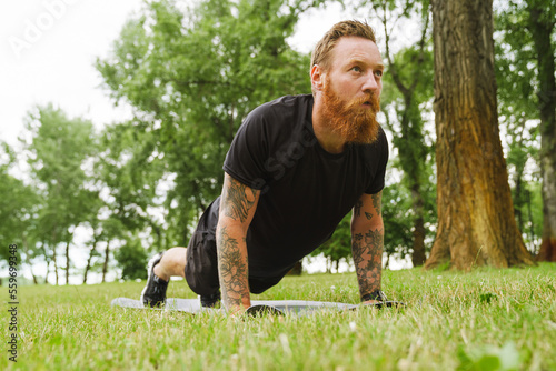 Ginger bearded man doing exercise during workout in park © Drobot Dean