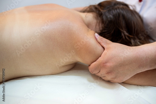 Body care procedure of a young female client lying on white sheets.