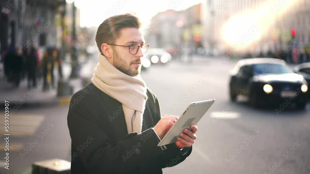 Man modern artist or designer stands in city center on busy street with cars, looks at interior of historic building and draws using graphics tablet. Inspiration and creativity outdoors. Hobby, work. Man modern artist or designer stands in city center on busy street with cars, looks at interior of historic building and draws using graphics tablet. Inspiration and creativity outdoors. Hobby, work.