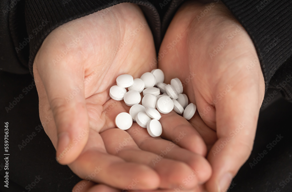 A lot of white pills in the hands of an adult man. A lot of white pills in the hands of an adult man.