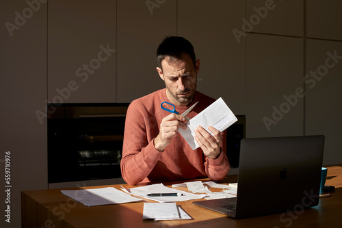 Man opening envelope with scissors at home photo