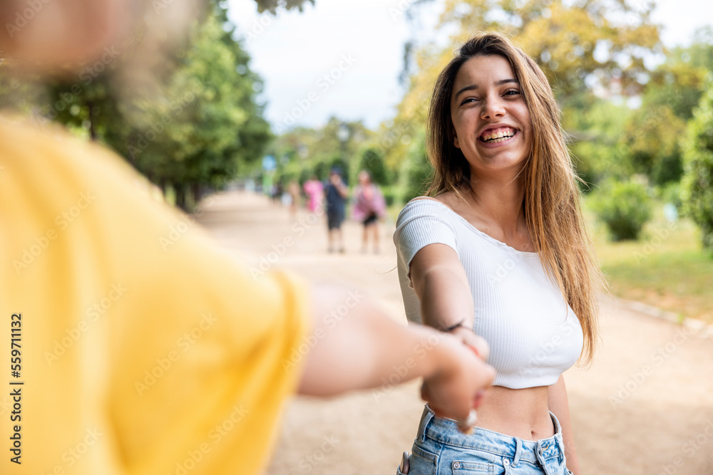 Happy woman holding friends hand in park Happy woman holding friends hand in park