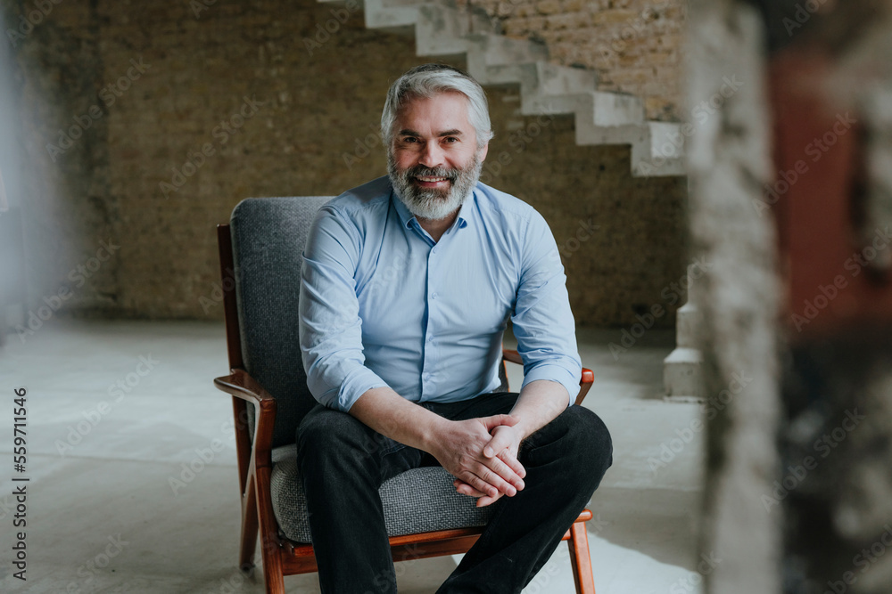 Happy mature businessman sitting in chair at under construction site