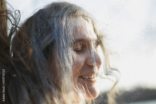 Close up tousled gray haired woman laughing with closed eyes portrait picture. Closeup side view photography with blurred background. High quality photo for ads, travel blog, magazine, article