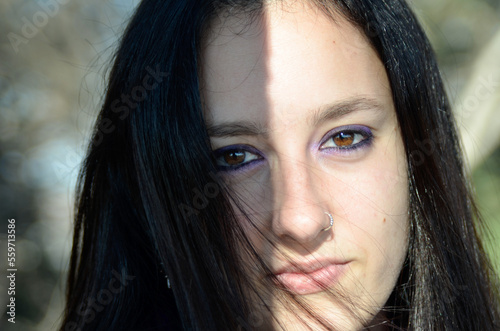 Woman with eyes made up in lilac color as part of the color of feminism. Shadow and light on half of the face. Brown eyes and deep look. Concept of feminism and gender violence. March 8, International © Laia Balart
