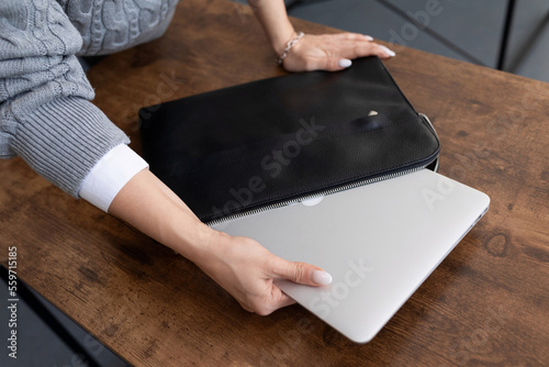 a woman takes out a laptop from a briefcase on the desktop