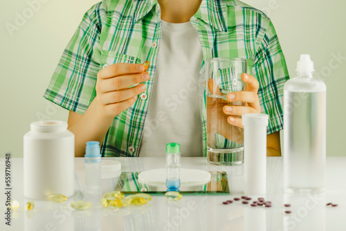 Oftalmology concept with boy siting at the table with containers with contact lenses, eye drops, clean solutions, supplements and vitamins for good vision. Eye care and eye treatment photo