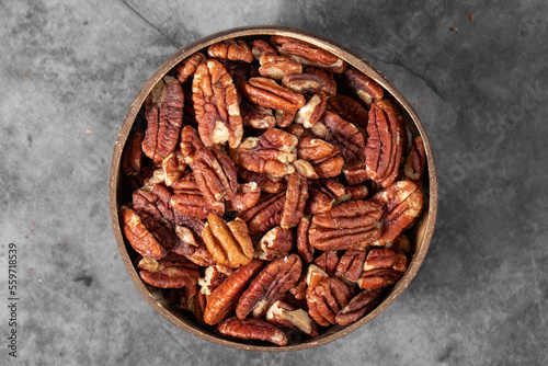 Pecan on dark background. Pecans in a coconut bowl. healthy fat. Heap shelled Pecans nut. Close up. Keto diet. Studio shoot. Top view