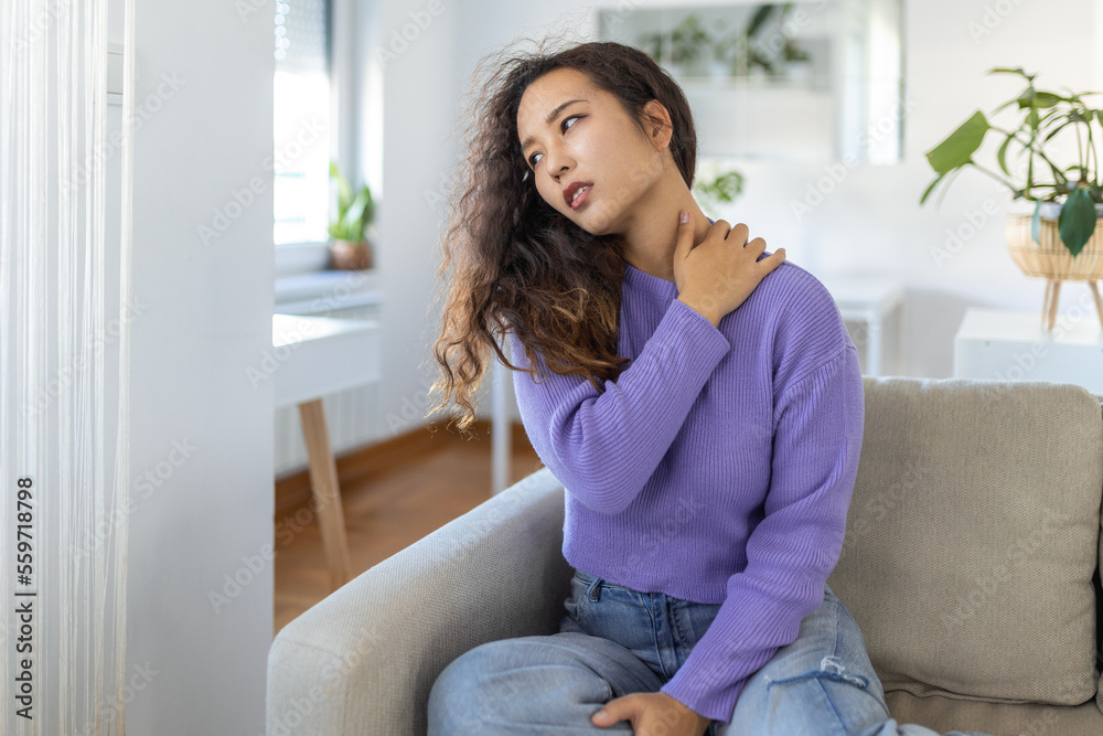Asian woman suffering from backache at home. Lower Back Pain . Woman feels back pain massaging aching muscles, sad woman suffers from low-back Asian woman suffering from backache at home. Lower Back Pain . Woman feels back pain massaging aching muscles, sad woman suffers from low-back