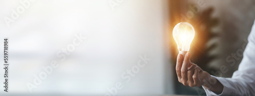 Woman holding glowing lamp, Creative new idea. Innovation, brainstorming, strategizing to make the business grow and be profitable. Concept execution, strategy planning and profit management. photo