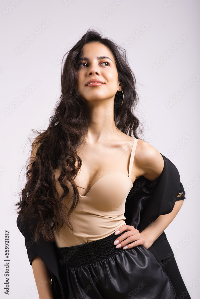Portrait of a young stylish brunette girl with wavy hair on a white studio background. Portrait of a young stylish brunette girl with wavy hair on a white studio background.