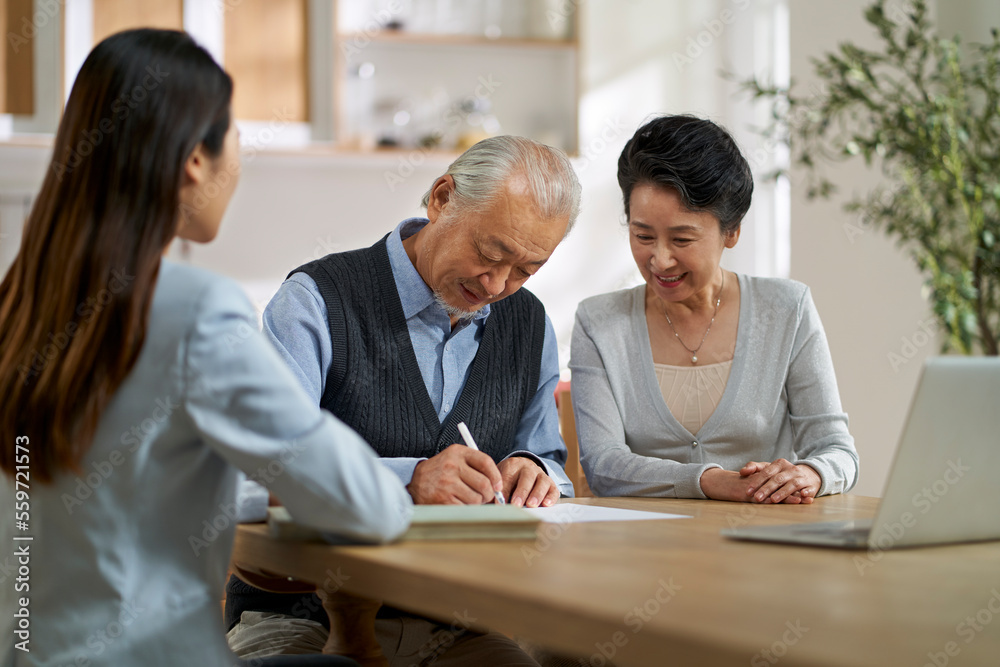 senior asian couple signing a contract at home senior asian couple signing a contract at home