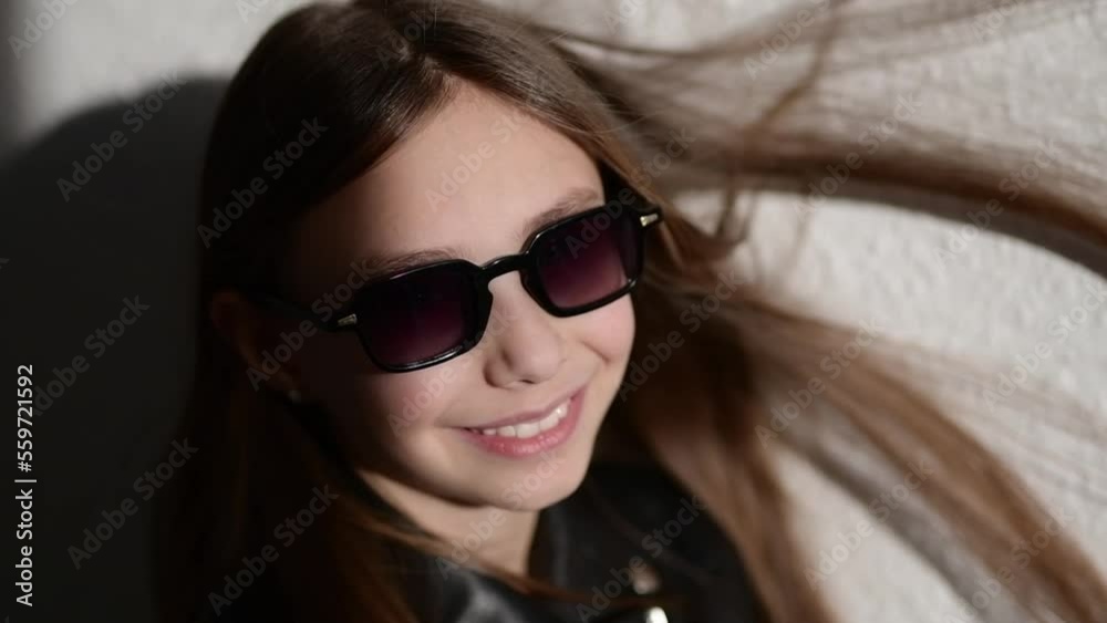 Slow motion video of a stylish child in leather jacke with glasses , the wind blows in her face and inflates the hair Slow motion video of a stylish child in leather jacke with glasses , the wind blows in her face and inflates the hair